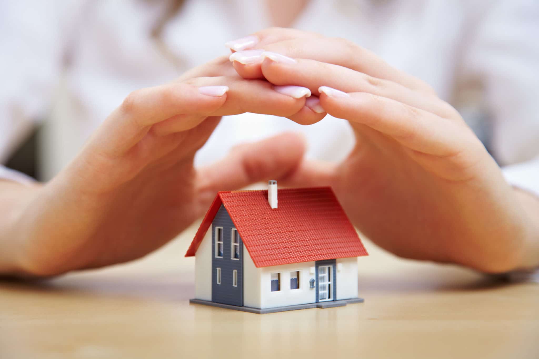 hands over small house, signifying protectio