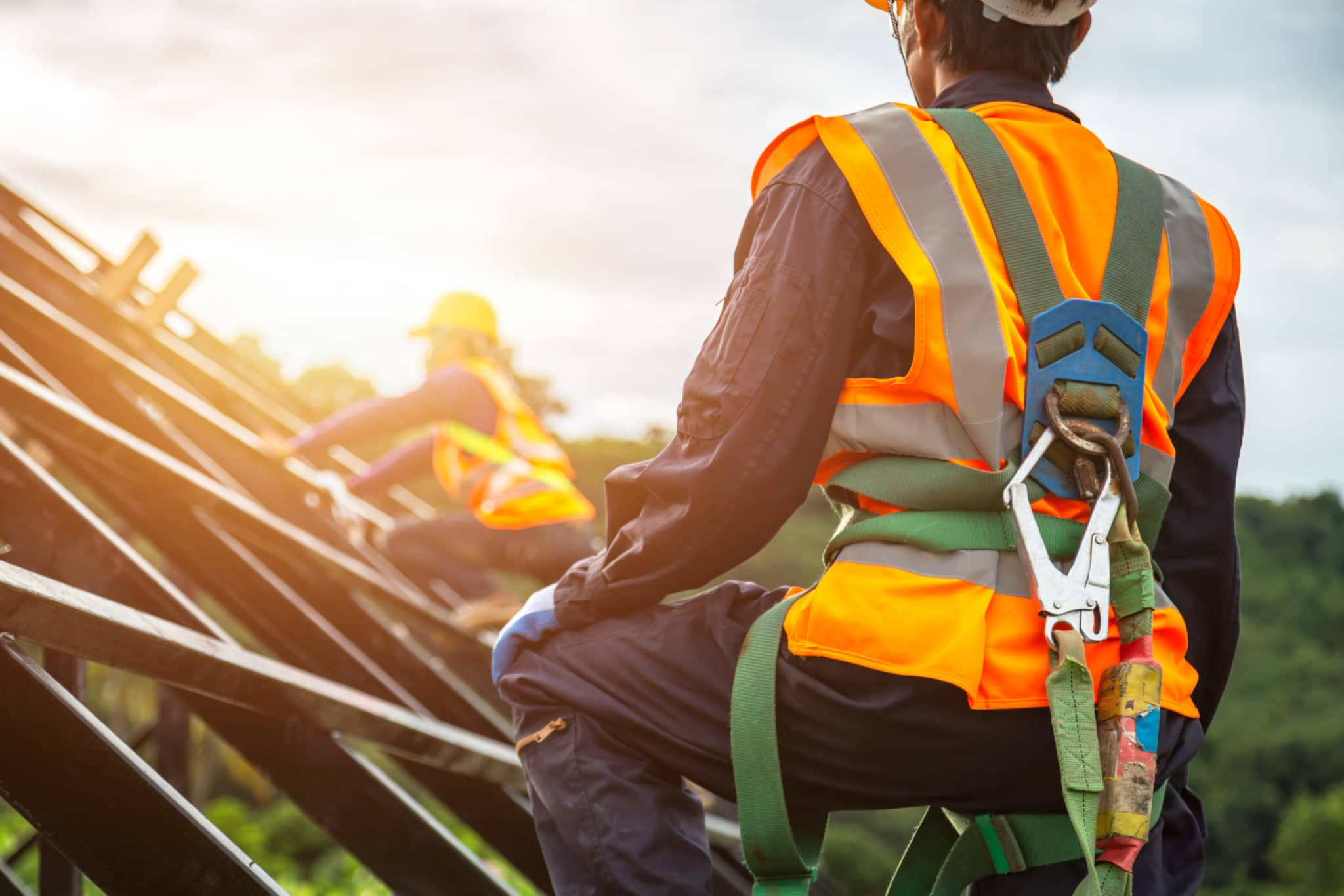 [safety body construction] Working at height equipment. Fall arrestor device for worker with hooks for safety body harness on selective focus. Worker as in construction background.