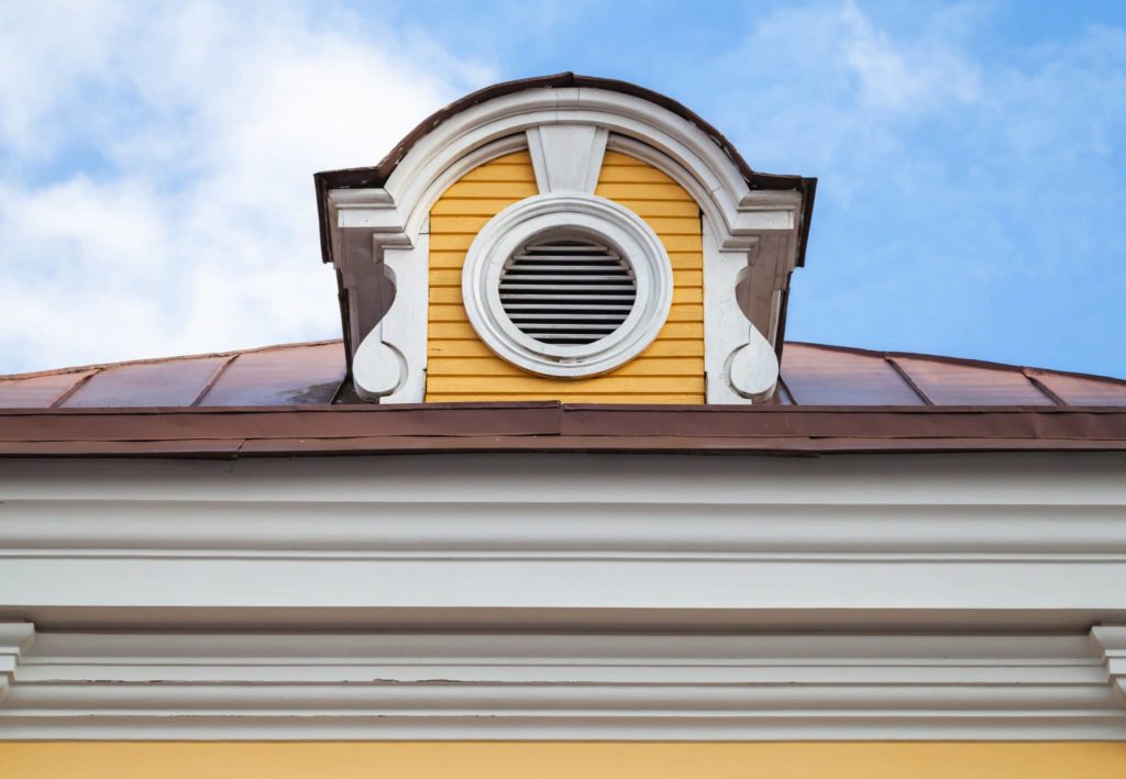 Vintage attic ventilation window on a roof slope in decorative round white wooden frame