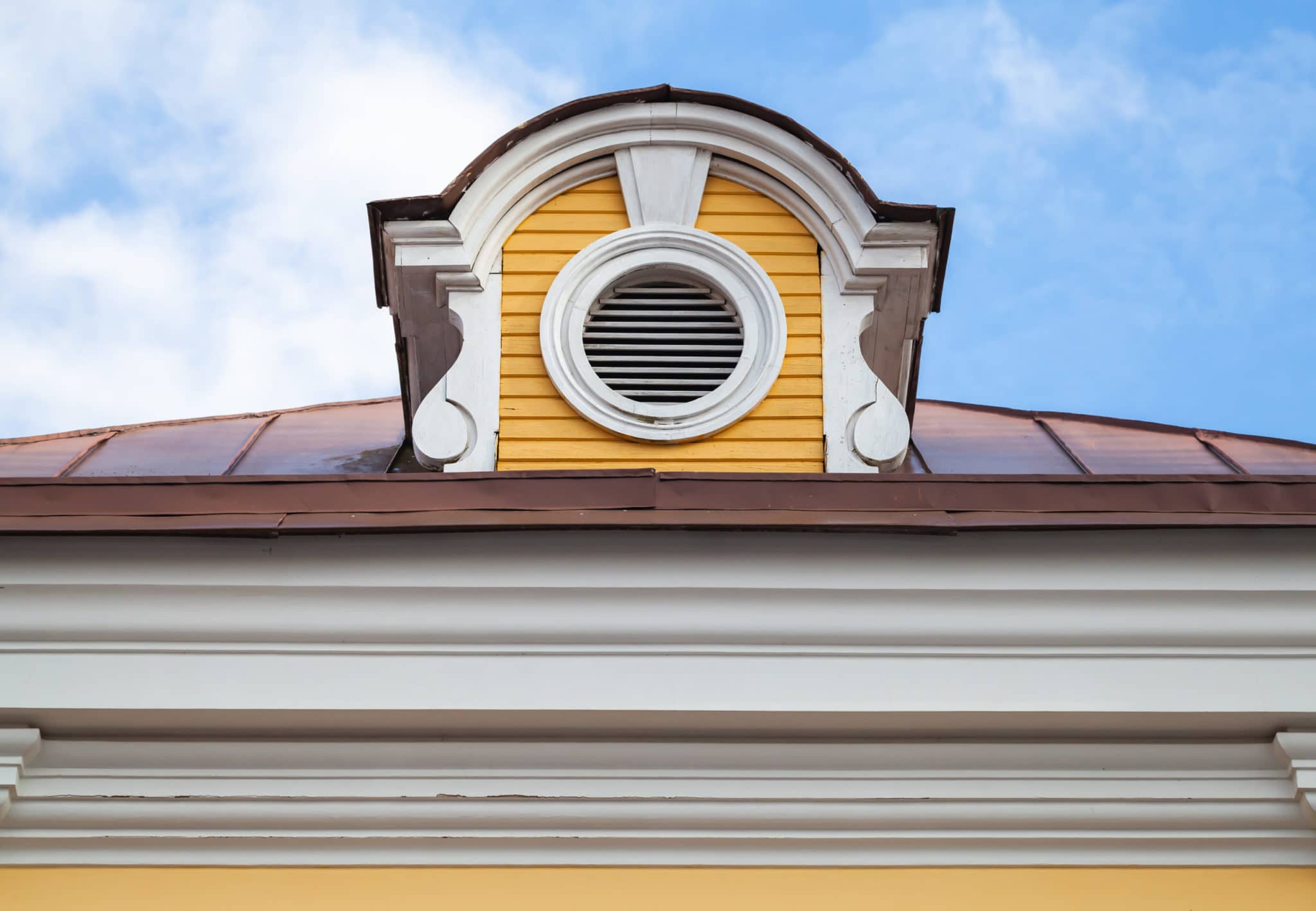 Vintage attic ventilation window on a roof slope in decorative round white wooden frame