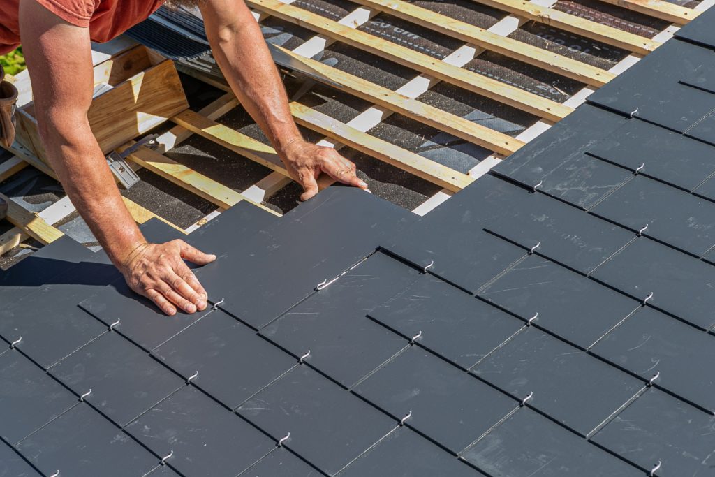 A roofer installing tiles for a commercial roof repair job.