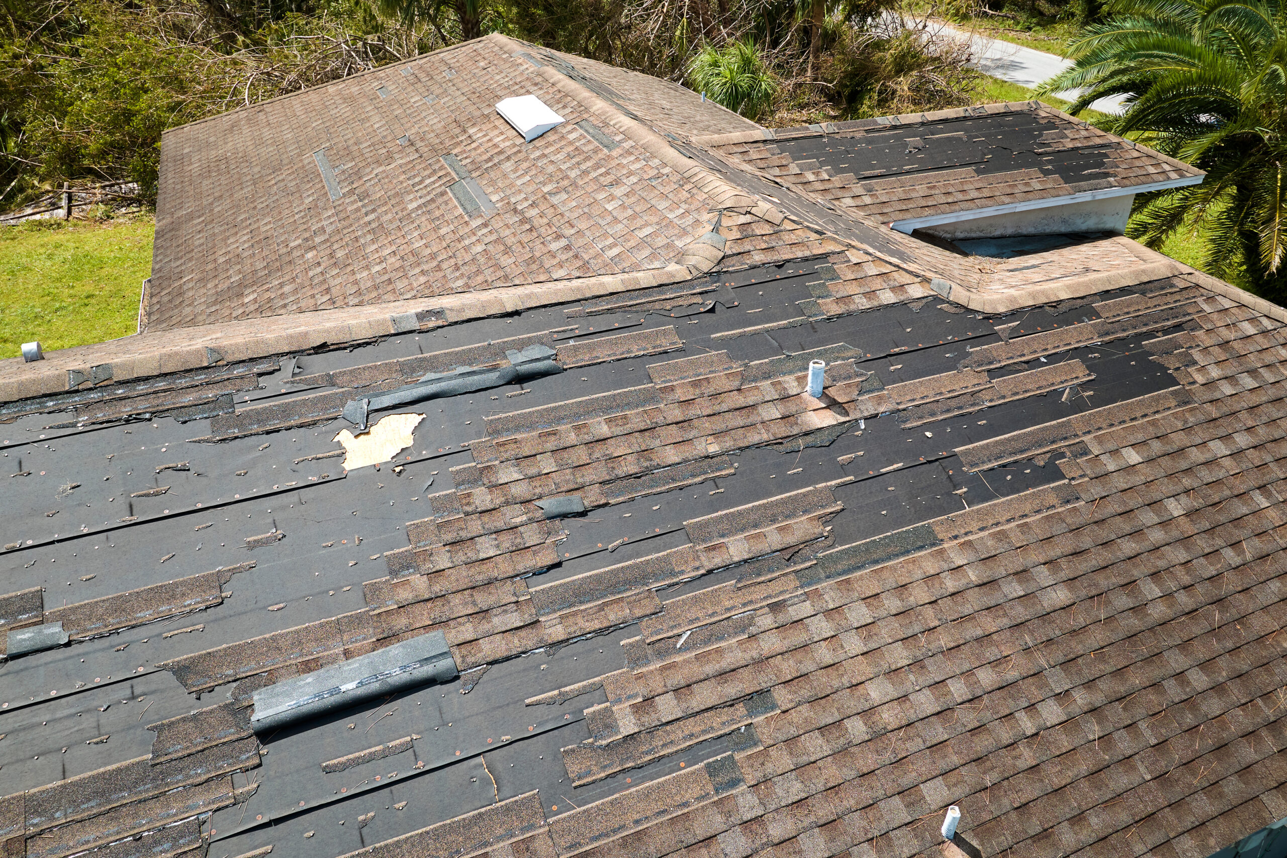 Damaged house roof with missing shingles after hurricane Ian in Florida. Consequences of natural disaster