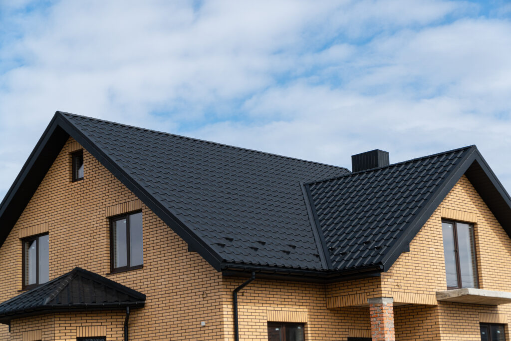 The modern house with plastic windows and a black roof of corrugated sheet.