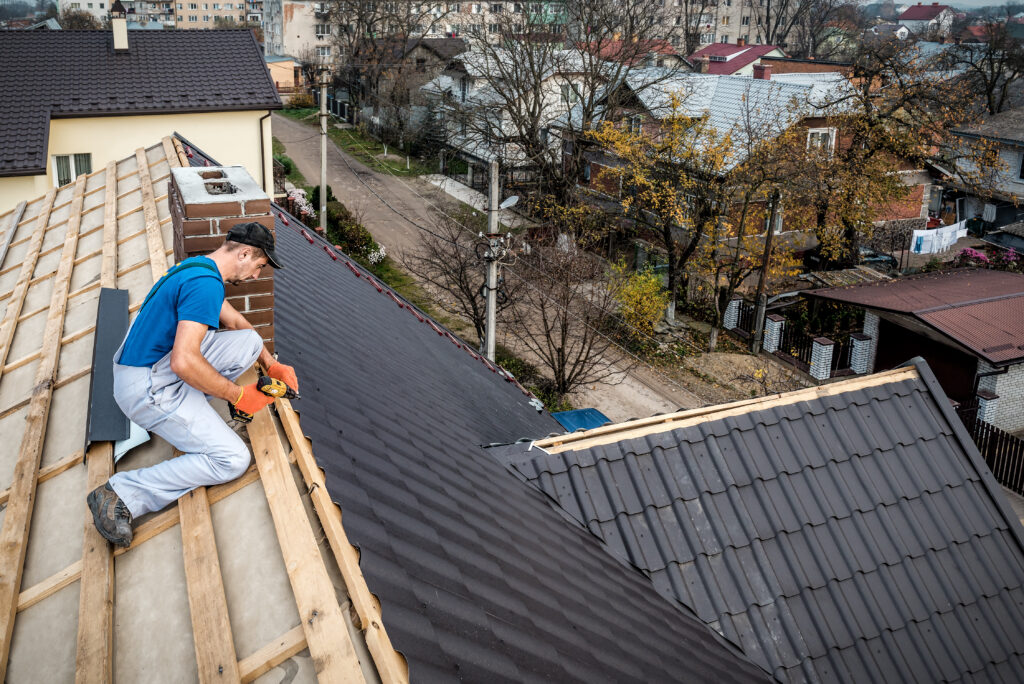 a professional handyman master (roofer) with electric screwdriver covers repairs the roof